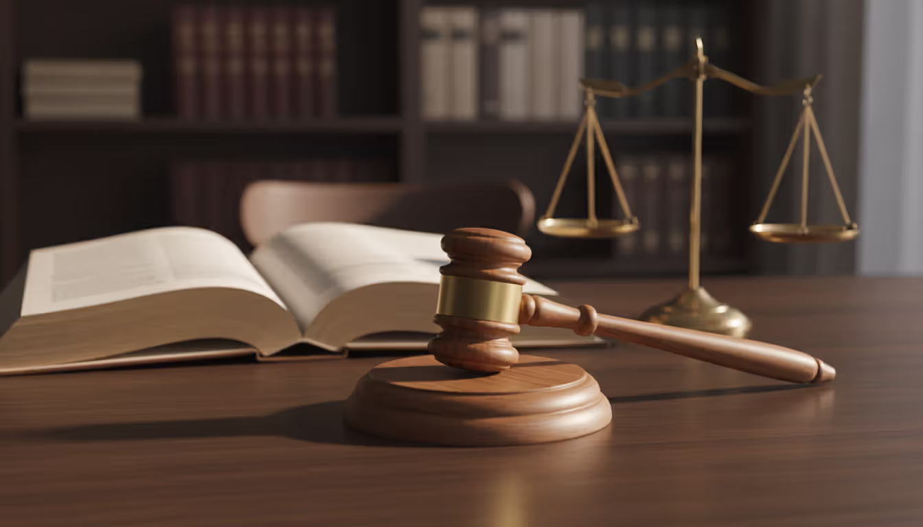 Judges wooden gavel on a sound block next to an open law book with scales of justice blurred in the background